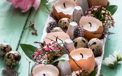 Osterdeko selber basteln mit Naturmaterialien: Eierschalenkerzen, Wachteleier und zarte Blüten auf Holz.