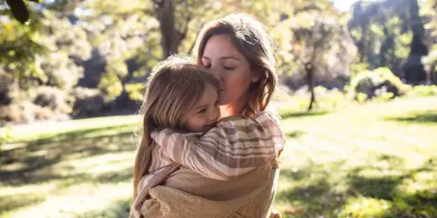 Mutter küsst ihr Kind zärtlich im Arm. Ein Moment voller Liebe, der die Essenz von gentle parenting deutsch widerspiegelt.