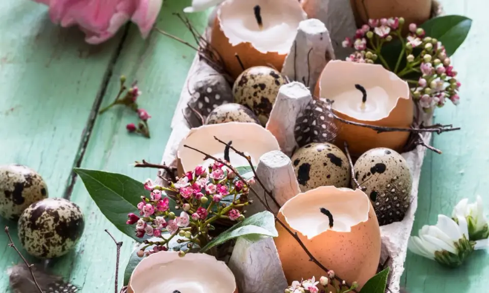 Osterdeko selber basteln mit Naturmaterialien: Eierschalenkerzen, Wachteleier und zarte Blüten auf Holz.
