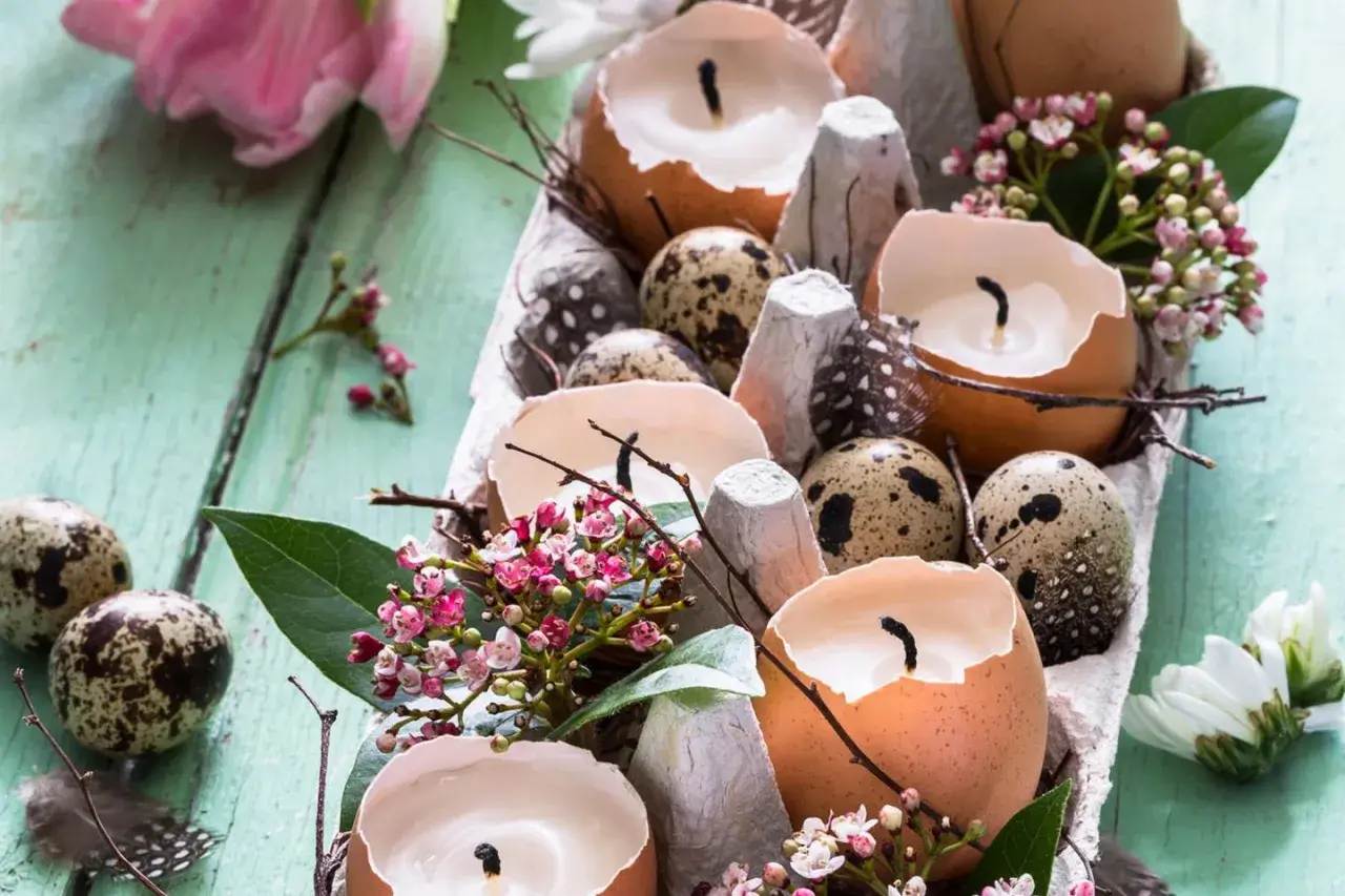 Osterdeko selber basteln mit Naturmaterialien: Eierschalenkerzen, Wachteleier und zarte Blüten auf Holz.